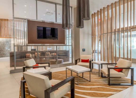 a lobby with chairs and tables and a television at The Acadia at Metropolitan Park, Arlington, Virginia